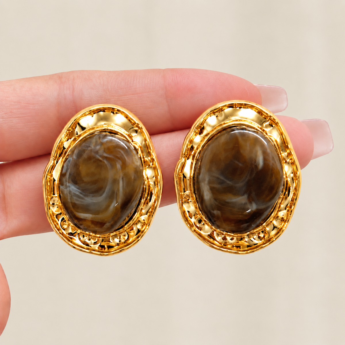 Close-up of brown imitation stone earrings with textured gold-tone frames