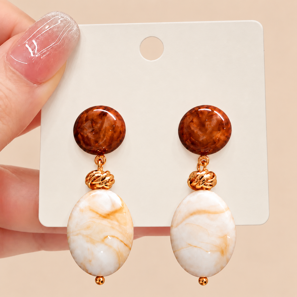 Brown and ivory imitation stone drop earrings shown in hand