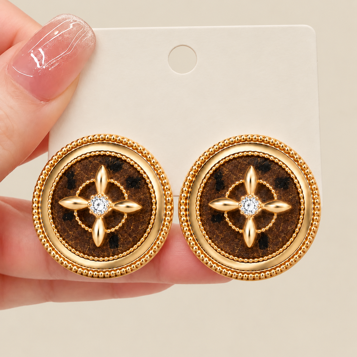 Brown round stud earrings shown in hand for scale