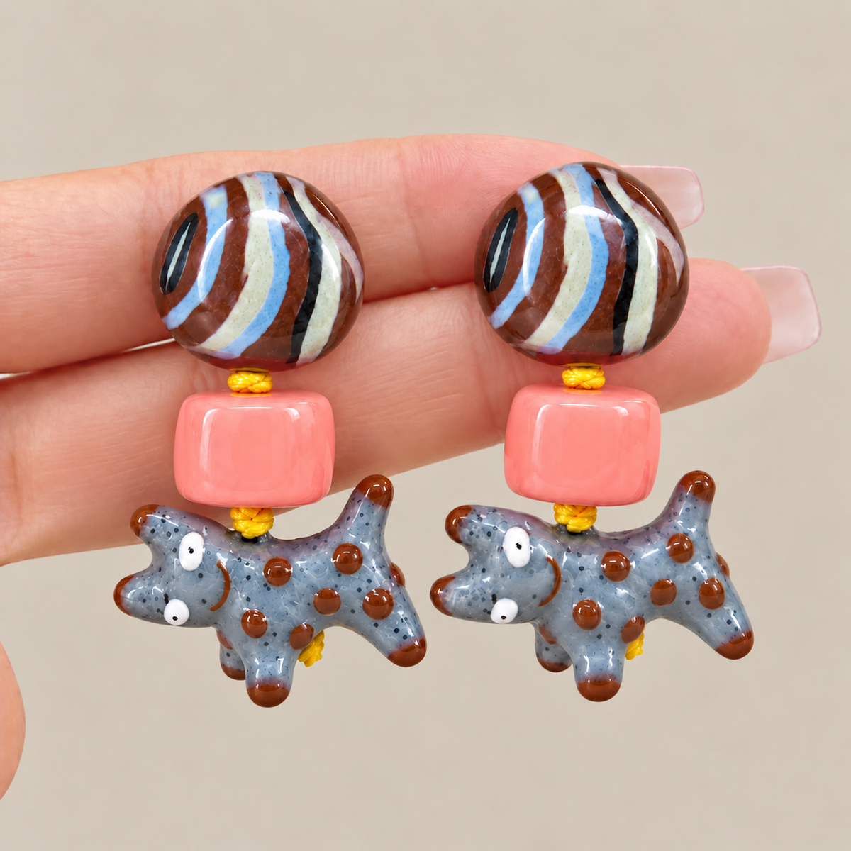Close-up of colorful dog drop earrings held in hand