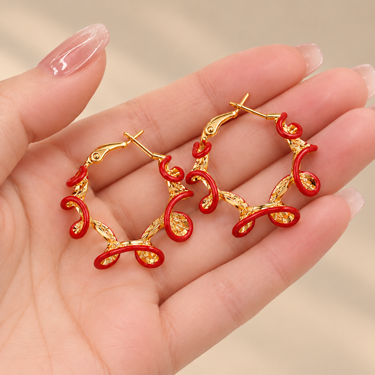 Red and gold hoop earrings held in hand