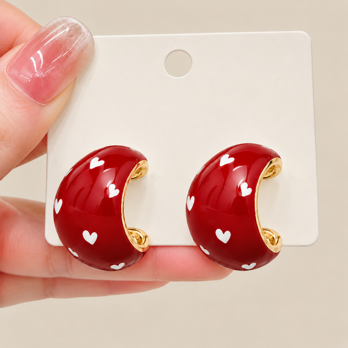Red heart stud earrings styled with an elegant neutral outfit