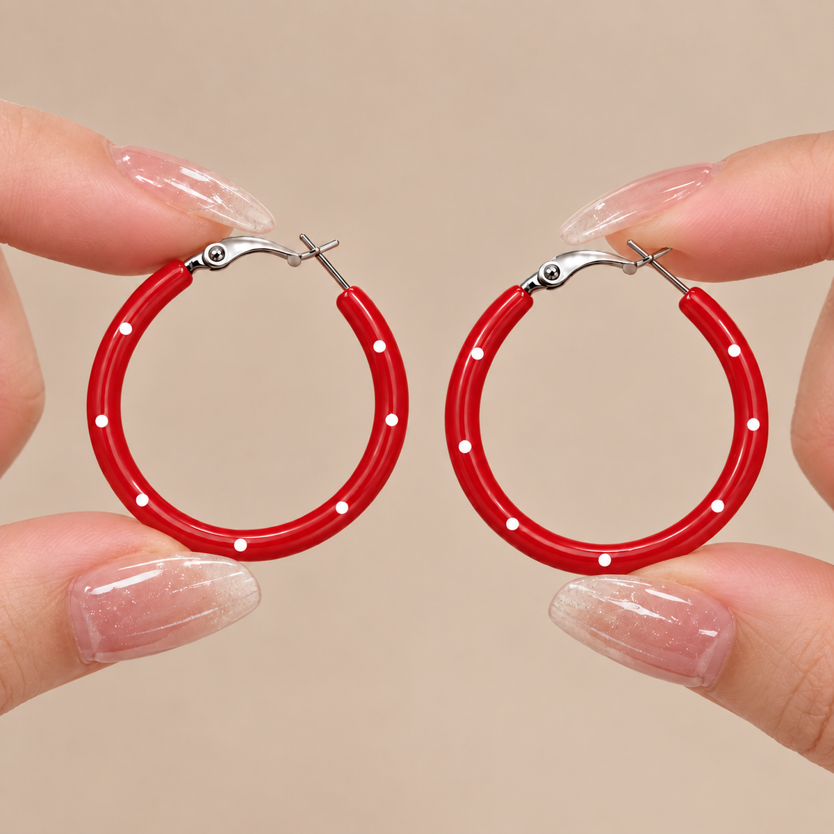 Red and white polka dot hoop earrings held by hand