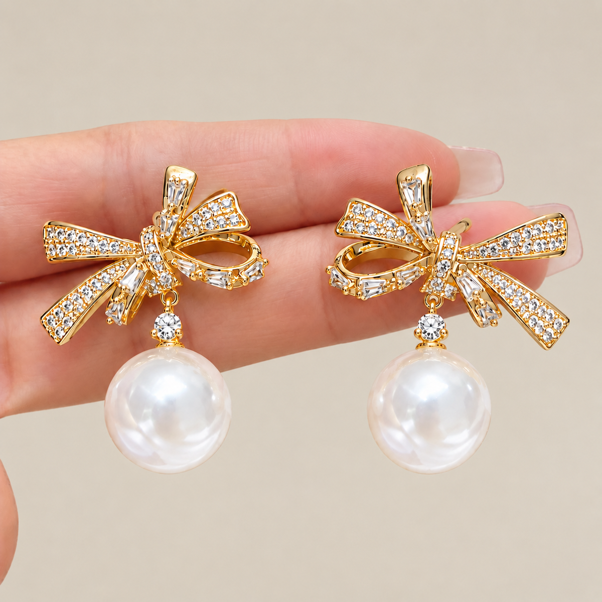 Close-up of gold-tone rhinestone bow earrings with faux pearl drops