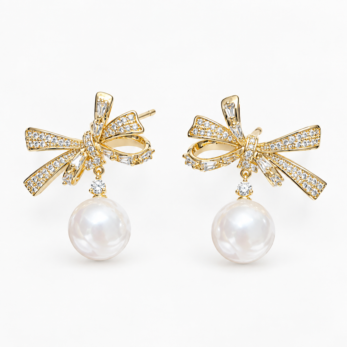 Gold-tone rhinestone bow faux pearl drop earrings on white background