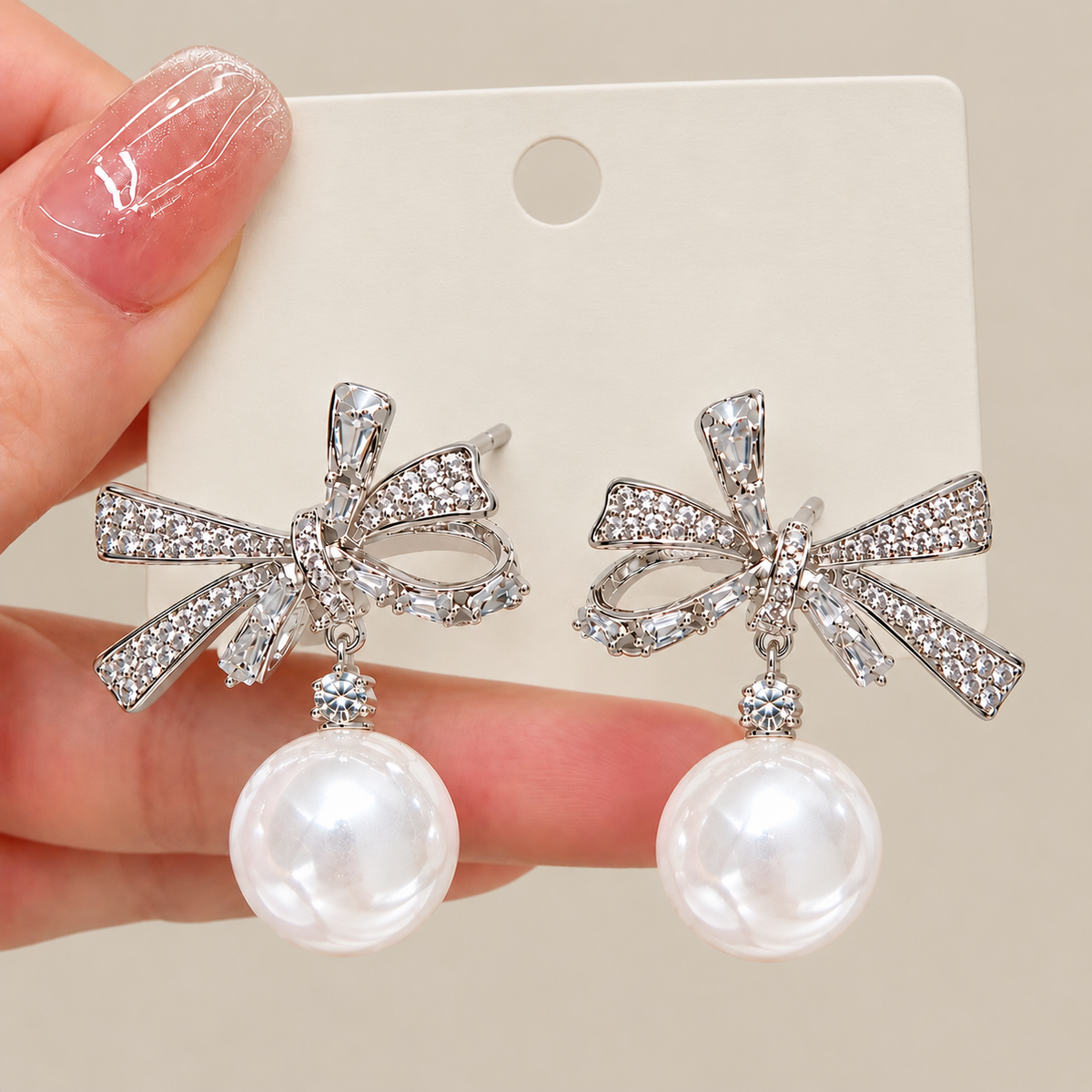 Close-up of silver-tone rhinestone bow earrings with faux pearl drops