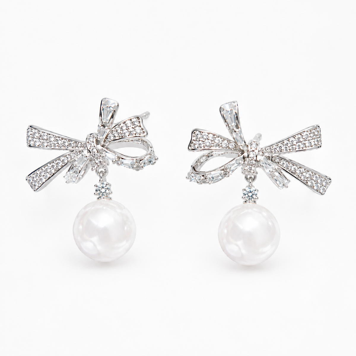 Silver-tone rhinestone bow faux pearl drop earrings on white background